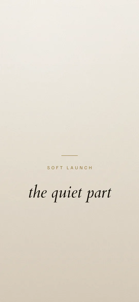 A minimal light vision board lock-screen wallpaper: warm porcelain gradient with SOFT LAUNCH in small tracked capitals above the line the quiet part in italic serif